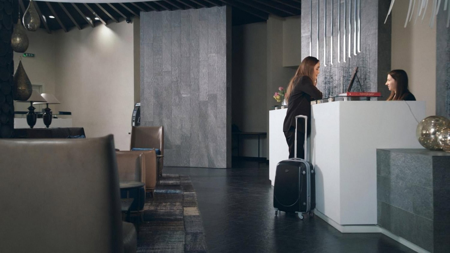 Guest with rolling suitcase checking in at a modern US hotel front desk
